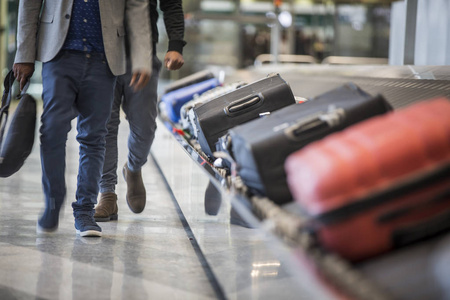 机场航站楼行李传送带上的轮式手提箱和袋子