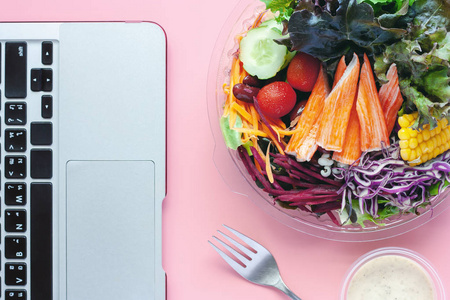 新鲜沙拉蔬菜与计算机笔记本电脑在工作场所为饮食和健康的午餐饮食概念
