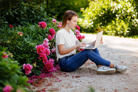 特写肖像的欢快的学生女孩躺在紫色花卉公园与笔记本电脑