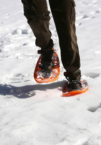 徒步旅行者与穿雪鞋和天鹅绒裤漫步在新鲜的山雪上