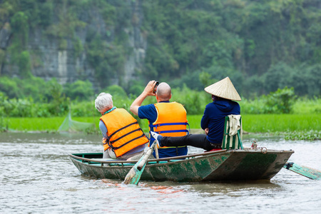 游客们乘船沿着非政府组织的东江水, 拍照的谭环, 划船者用脚来推动桨。越南宁平潭环