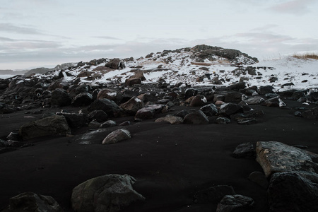 冰岛 Stokksnes 冰雪景观前黑色沙滩上的岩石