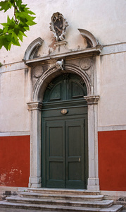 威尼斯的老教堂门。意大利。门上装饰有浮雕和装饰元素。门上方是头骨雕塑