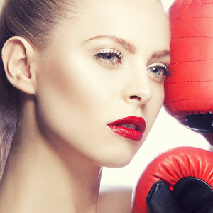 红色嘴唇化妆的年轻妇女和拳击手套在白色背景