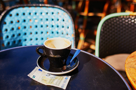 空杯黑咖啡和5欧元在巴黎的一个户外咖啡馆的桌子上, 法国