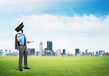 相机为首的人站在绿色的草地上反对现代城市景观