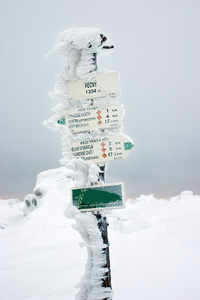 徒步旅行中雪覆盖的白霜方向路标