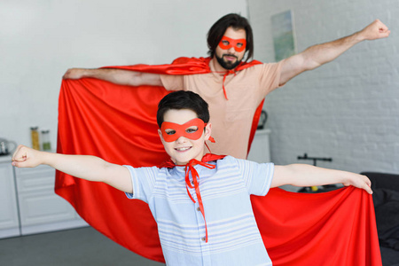 家庭中红色超级英雄服饰中的小儿子和父亲的选择性聚焦