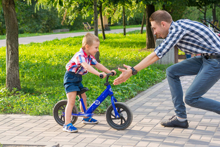 爸爸抓住了他的小儿子, 他在夏天骑自行车去公园兜风。