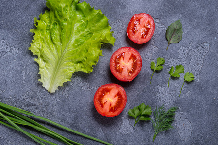 绿色新鲜沙拉, 西红柿和香料在黑石头背景