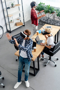 在工作场所使用虚拟现实耳机的年轻团队的高角度视图