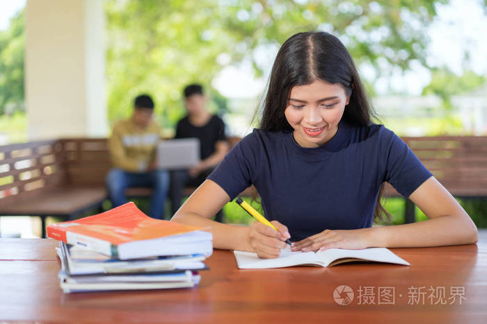 照片 女学生在图书馆读书笔记, 年轻亚洲妇女坐在桌上做作业在大学
