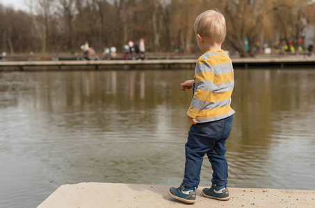 小男孩在公园附近的湖边玩耍