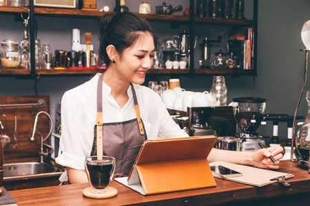 咖啡店柜台酒吧使用数字平板电脑的咖啡师妇女