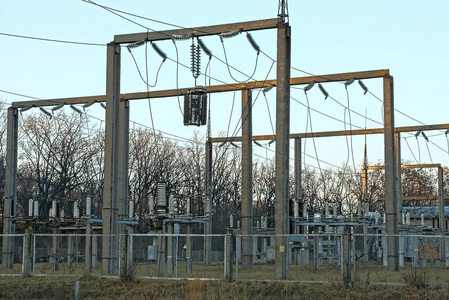 在栅栏后面有电线杆变压器和电线的发电厂的一部分