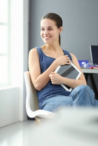年轻的女人坐在办公桌前与文书 计划和笔记本电脑