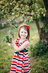 在盛开的苹果树上的礼服和头巾的可爱女孩的肖像