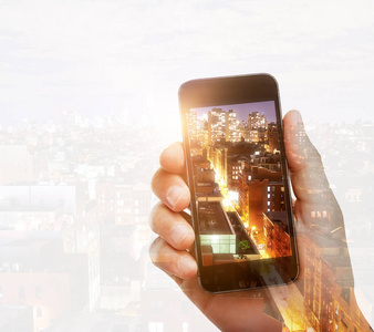 手持智能手机拍摄城市的照片。摄影和艺术概念。双重曝光