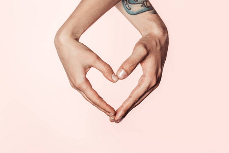女性和纹身男子拍摄的照片粉红色背景下的手做心脏符号