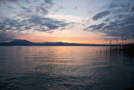 日出在湖和山。清晨的风景。山在剪影和上升的太阳的红色射线。在意大利的爱尔兰湖日出