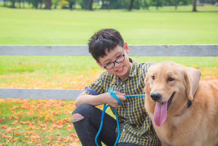 年轻的亚洲男孩坐在公园里和他的狗聊天
