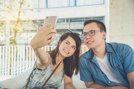 年轻的亚裔夫妇在咖啡馆里用手机拍照
