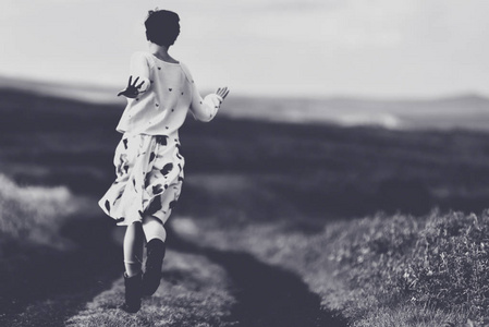 穿着裙子的女人在乡间小路上奔跑。自由概念。黑白相间, 色调柔和, 复古效果
