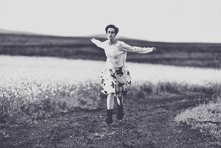 穿着裙子的女人在乡间小路上奔跑。自由概念。黑白相间, 色调柔和, 复古效果