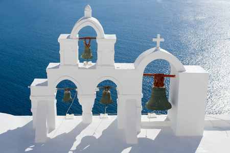 平静的海面，白色教堂的拱，十字架，钟声岛圣托里尼岛格雷克