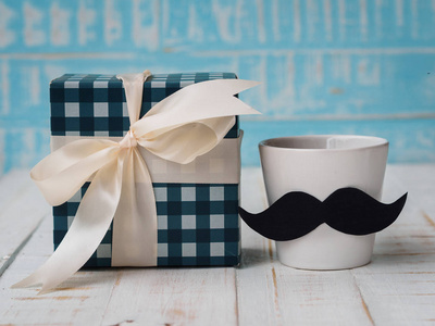 父亲节快乐的概念。礼品盒, 一杯咖啡与胡子在白色和蓝色背景