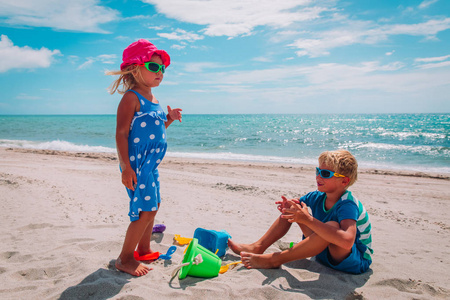 孩子男孩和女孩在海滩玩沙子
