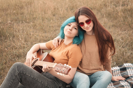 两个年轻女子躺在田野上弹吉他