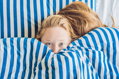 美丽的年轻女子在床上躺下来睡觉。得不到足够的睡眠概念