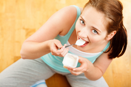 高关键肖像年轻白种女人在家里吃酸奶