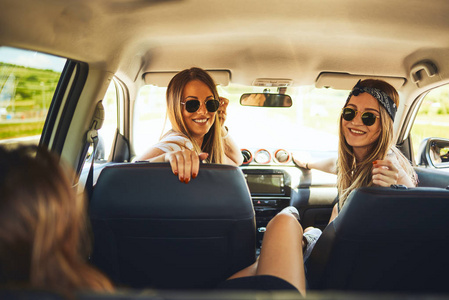 三名妇女享受公路旅行。他们坐在车里聊天。