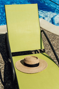 稻草帽子躺在太阳躺椅在池边