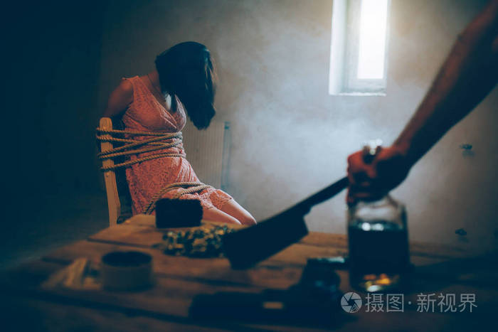 一个女孩坐在椅子上 绑在绳子上的照片.她没有知觉.