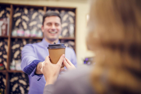 照片的咖啡师男子伸展玻璃对妇女的模糊背景