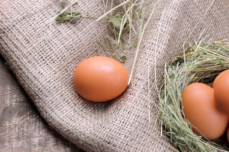 褐色鸡蛋旁边的鸡蛋在一个棕色的木质的草地巢