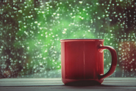 一杯热茶在窗外的背景雨中。选择性聚焦