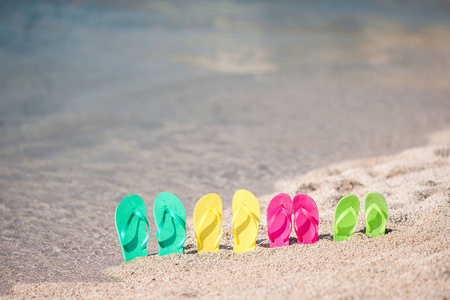 家庭多彩拖鞋在面海的海滩上