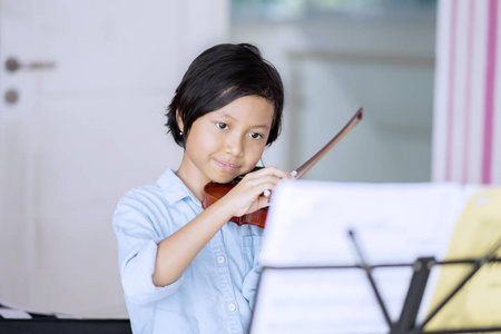 一个小女孩在家里练习小提琴的时候看纸钞的照片