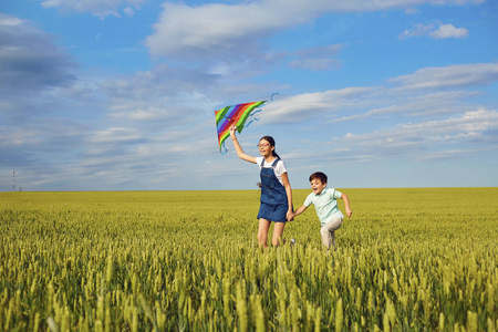 夏天, 带着风筝的孩子们跑过麦田。C