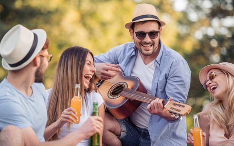 一群朋友在白天在公园里野餐和玩吉他