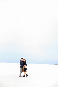 夫妇站在白色的冬季单音背景和拥抱