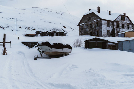 旧的破旧和部分毁坏的房子, 人们仍然住在北方的村庄, 在寒冷的厚泥的白雪下冬季
