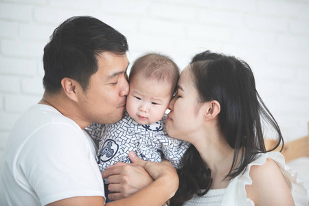 快乐亚洲家庭父亲母亲与女儿亲吻与微笑面孔