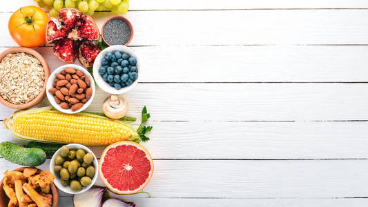 白色木桌上的健康食品。新鲜蔬菜, 水果, 坚果, 浆果, 蘑菇。顶部视图。文本的可用空间