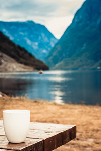 木制的桌子上的杯子。美丽的峡湾挪威斯堪的纳维亚景观的背景 湖泊和山脉