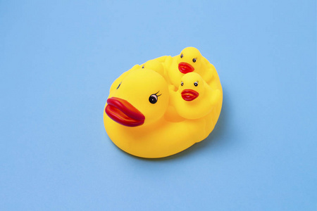 黄色的橡胶玩具, 妈妈鸭和小鸭子在蓝色的背景。母亲关爱儿童养育子女和教育儿童的概念